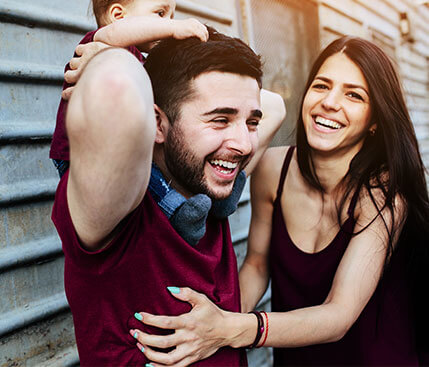 father-with-baby-shoulders-mother-laughing